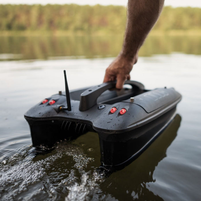 Deeper Quest Bait Boat hålls i handtaget vid vattenytan