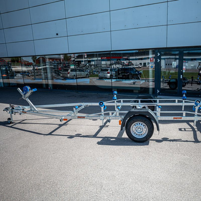 Neptun Navy 1300 båttrailer med blå kölrullar framför en byggnad, från sidan